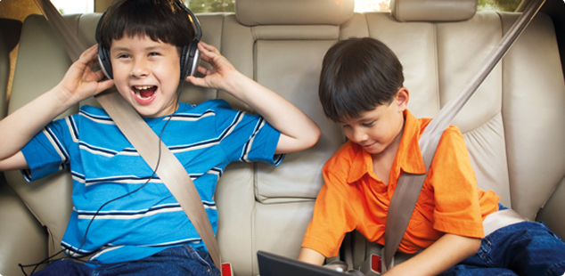 Des enfants se divertissent dans une voiture de location avec wifi mobile en option